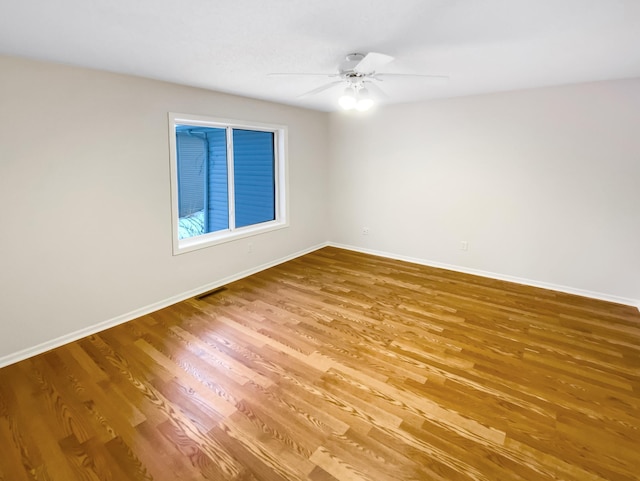 empty room featuring visible vents, ceiling fan, baseboards, and wood finished floors