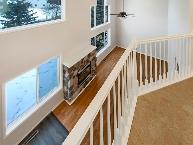 stairway featuring a fireplace and a ceiling fan