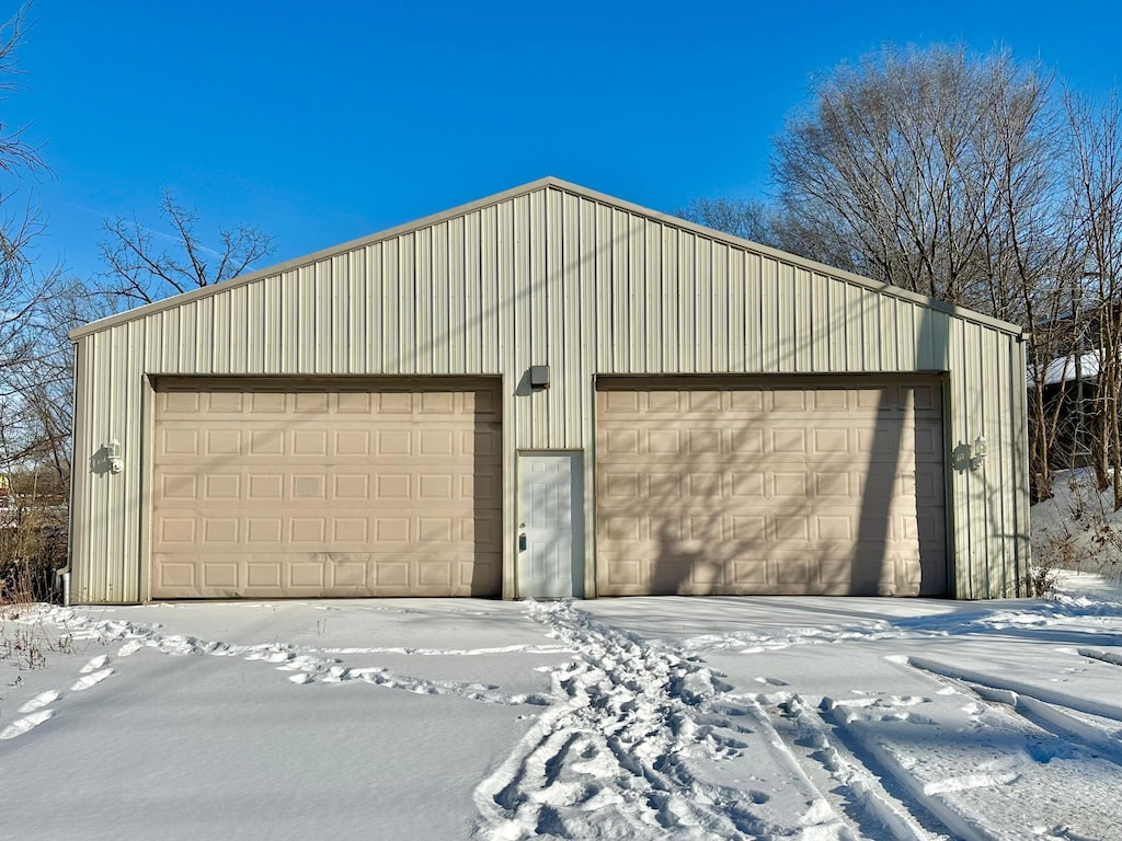 snow covered garage featuring a detached garage