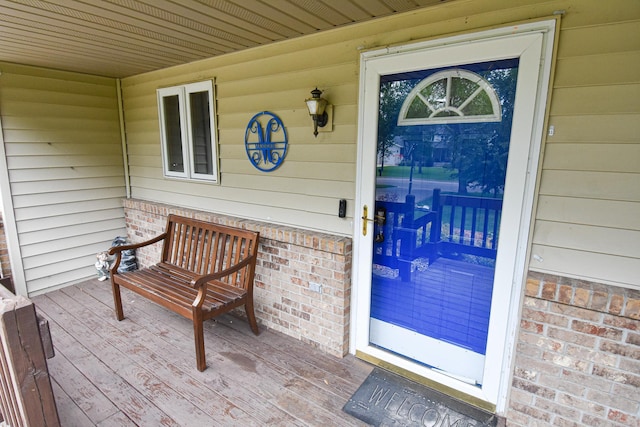 view of exterior entry featuring brick siding and a porch