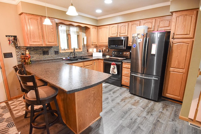 kitchen with dark countertops, decorative light fixtures, a peninsula, stainless steel appliances, and a sink