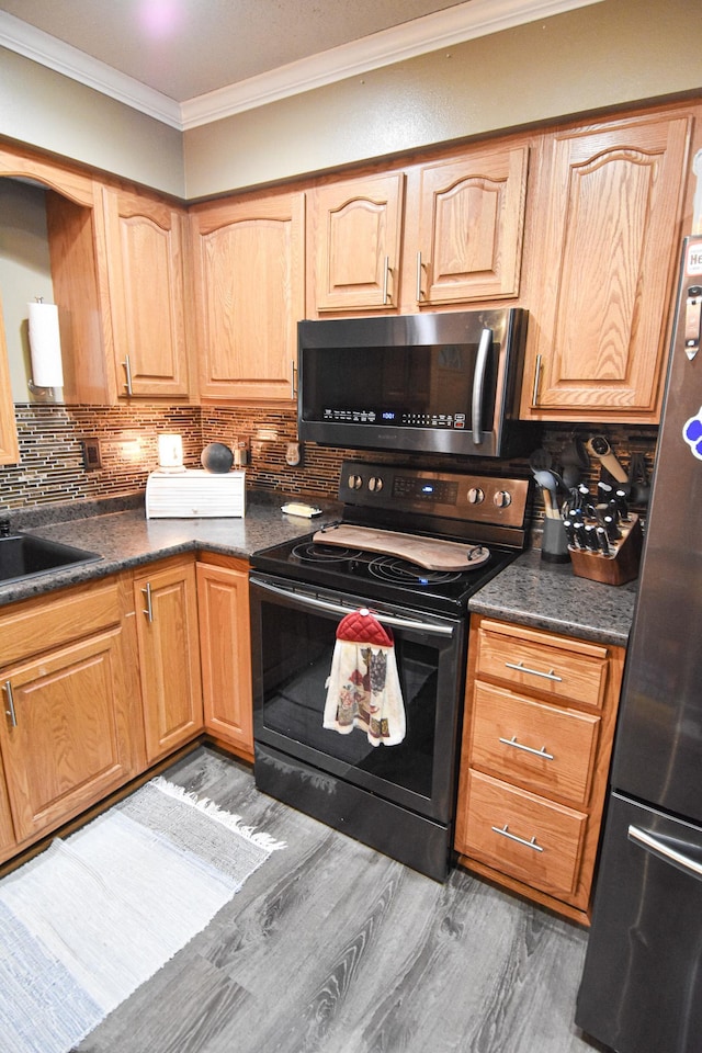 kitchen with dark wood-style flooring, dark countertops, decorative backsplash, appliances with stainless steel finishes, and ornamental molding