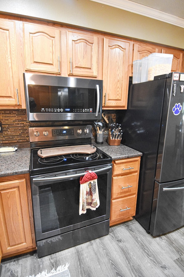 kitchen featuring crown molding, dark countertops, stainless steel microwave, electric range, and freestanding refrigerator