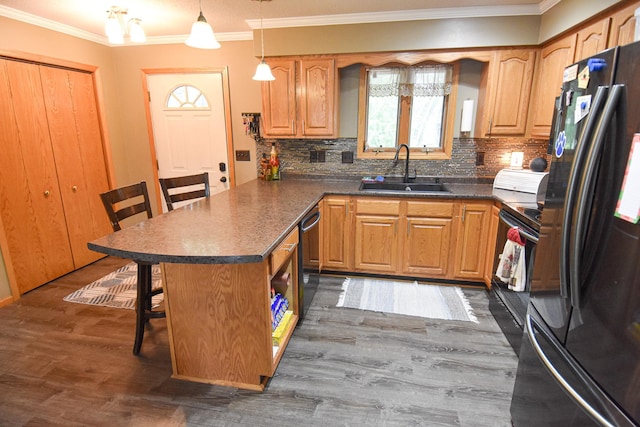 kitchen with a sink, hanging light fixtures, black appliances, dark countertops, and a kitchen bar