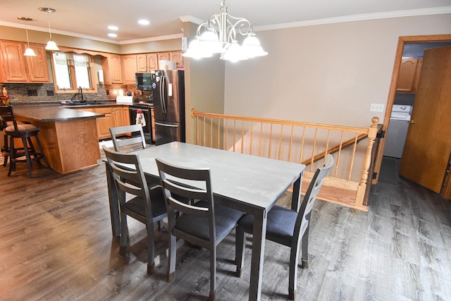 dining area featuring dark wood-style floors, ornamental molding, washer / clothes dryer, an inviting chandelier, and recessed lighting