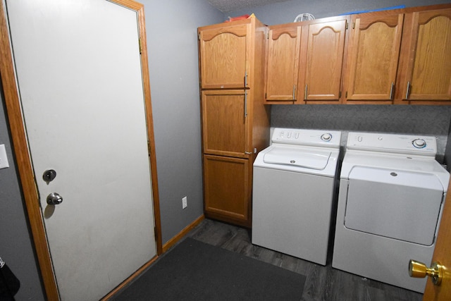 laundry area featuring dark wood-type flooring, washing machine and dryer, cabinet space, and baseboards