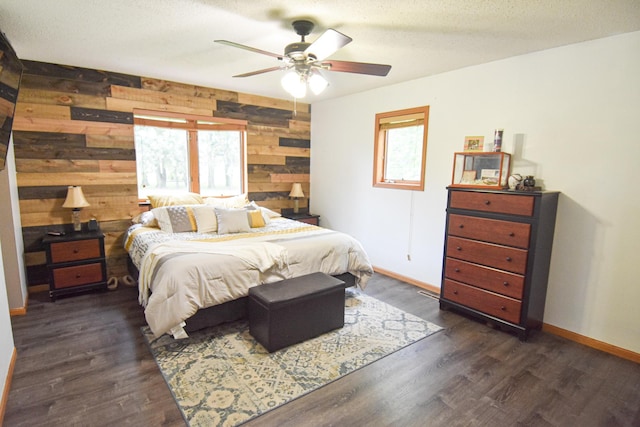 bedroom featuring a textured ceiling, ceiling fan, wood walls, dark wood-style flooring, and baseboards