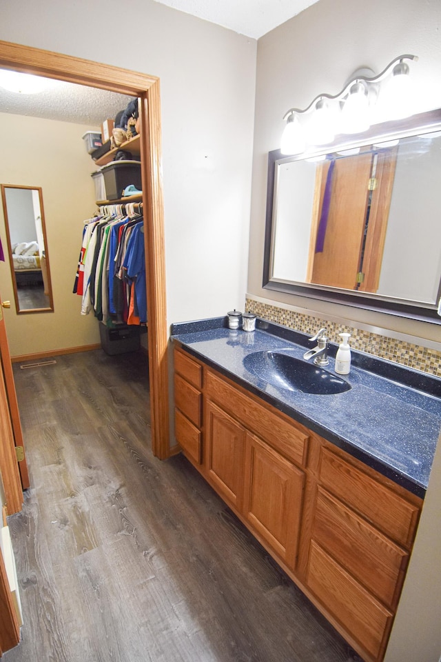 bathroom with wood finished floors, vanity, and a walk in closet