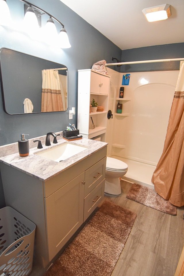 bathroom featuring toilet, a shower stall, wood finished floors, and vanity