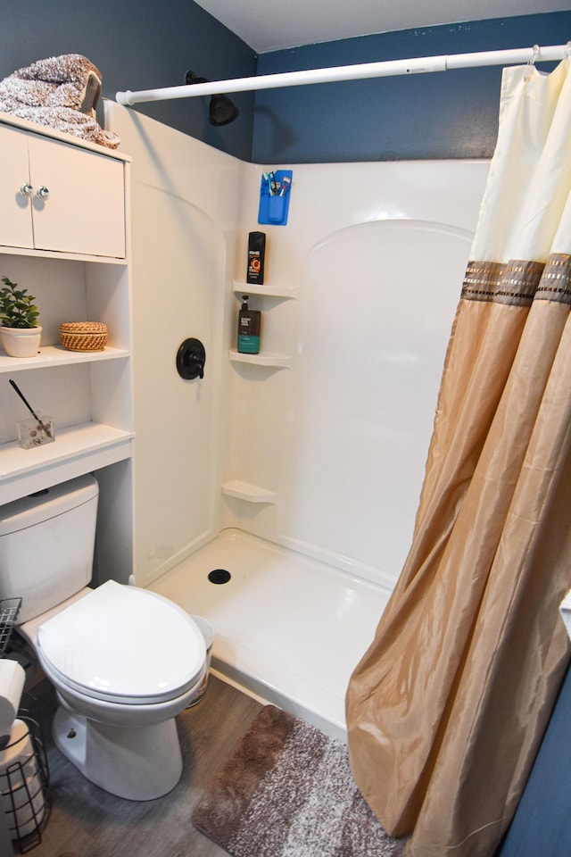 bathroom with a stall shower, wood finished floors, and toilet