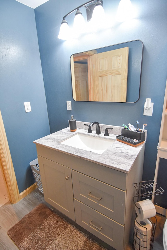 bathroom featuring baseboards, wood finished floors, and vanity