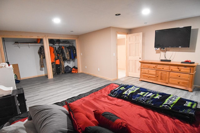 bedroom with light wood-style floors, baseboards, multiple closets, and recessed lighting