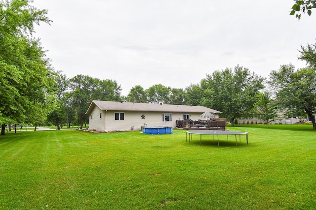 rear view of house with a covered pool and a yard