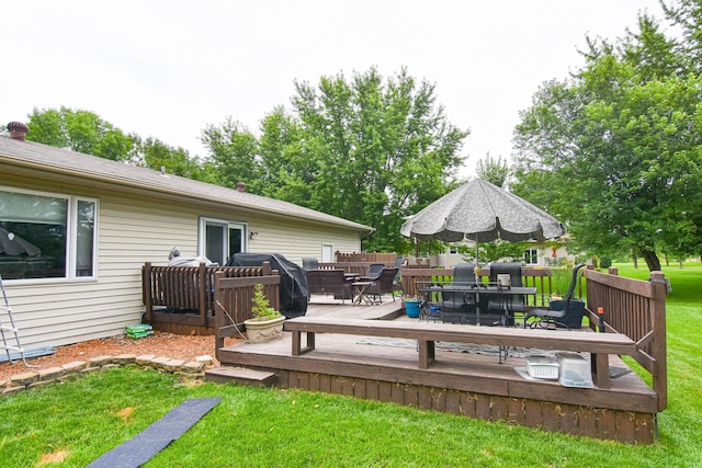 deck featuring outdoor dining area, area for grilling, and a lawn