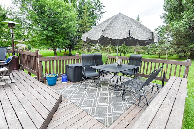 wooden terrace with outdoor dining space and a lawn