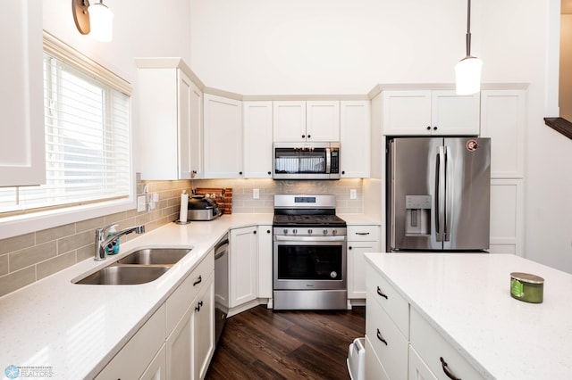 kitchen featuring dark wood-type flooring, a sink, white cabinets, appliances with stainless steel finishes, and backsplash