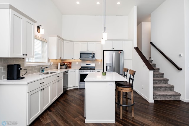 kitchen featuring appliances with stainless steel finishes, a kitchen bar, a sink, and dark wood finished floors