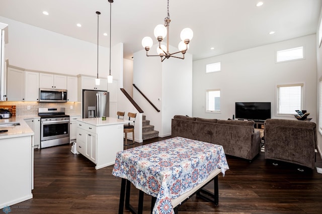 dining room with recessed lighting, dark wood-style flooring, a high ceiling, and stairs