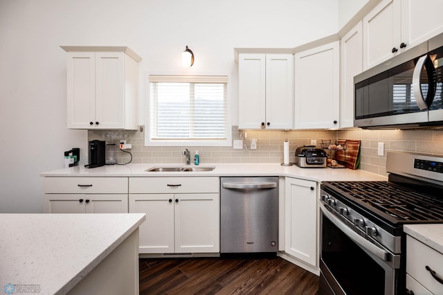 kitchen featuring tasteful backsplash, dark wood-style floors, appliances with stainless steel finishes, white cabinetry, and a sink