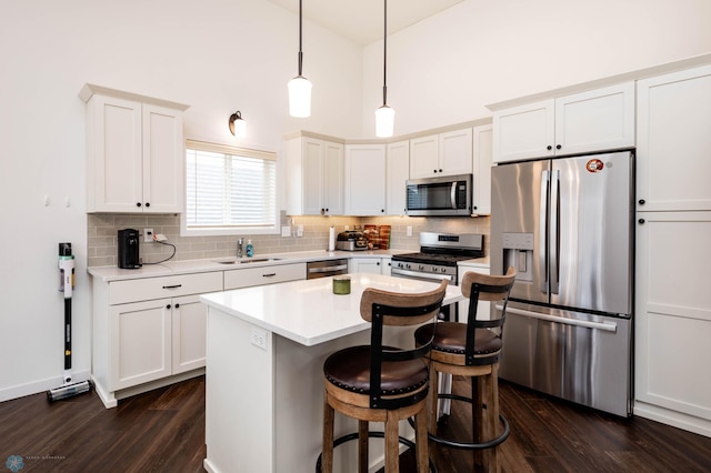 kitchen featuring stainless steel appliances, tasteful backsplash, light countertops, dark wood-type flooring, and a sink