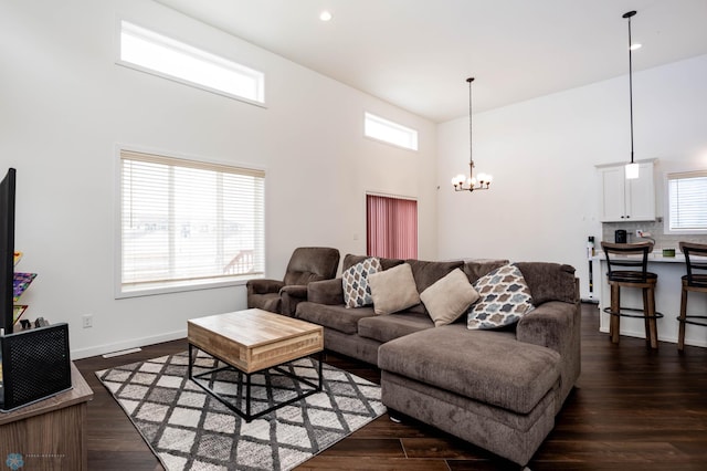 living area featuring a chandelier, dark wood-style flooring, and a towering ceiling