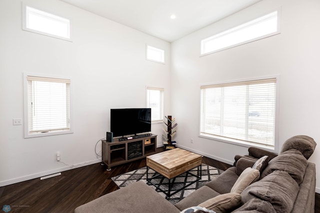 living area with a high ceiling, baseboards, dark wood-type flooring, and recessed lighting