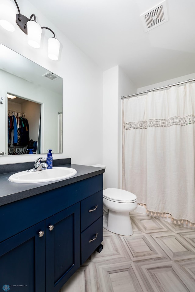 full bathroom featuring toilet, vanity, and visible vents