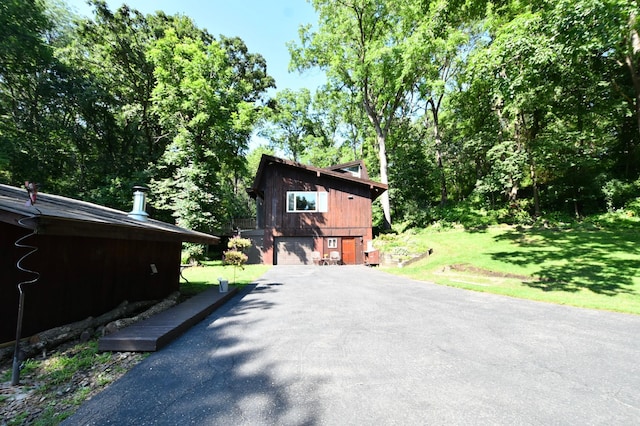 view of home's exterior with a garage, aphalt driveway, and a yard