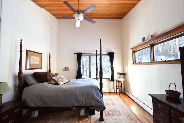 bedroom with a ceiling fan, a baseboard radiator, wood ceiling, and wood finished floors