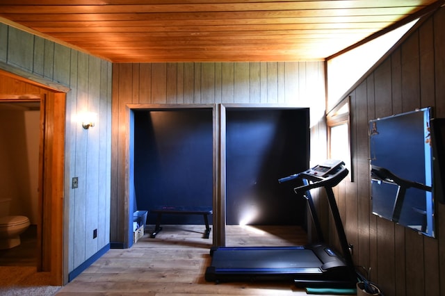 workout area featuring light wood finished floors, wood ceiling, and wooden walls