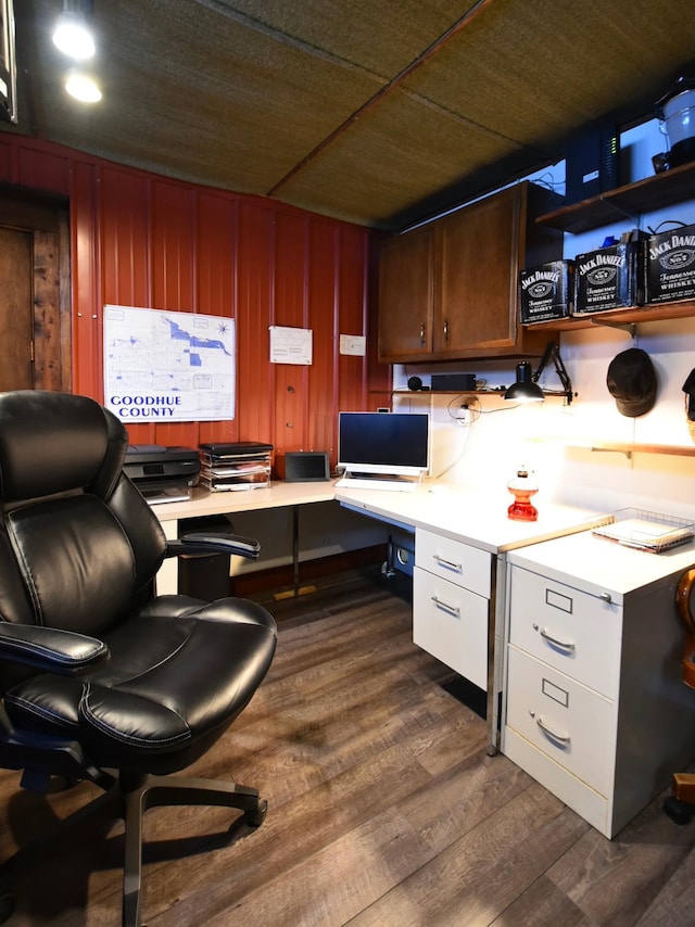 office with wooden walls, dark wood-type flooring, and built in desk