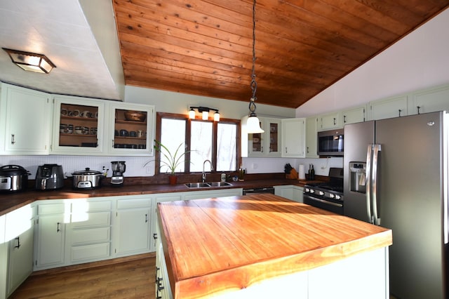 kitchen with green cabinetry, glass insert cabinets, decorative light fixtures, black appliances, and a sink