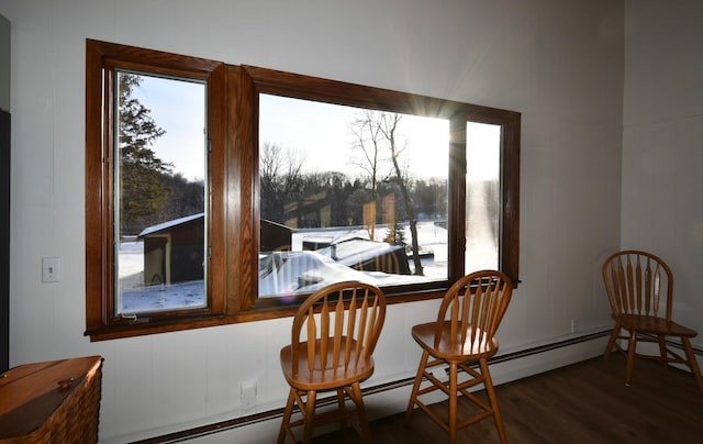 dining space with dark wood-style flooring, plenty of natural light, and a view of trees