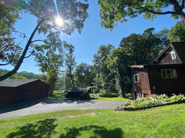 view of yard featuring an outbuilding, aphalt driveway, and a garage