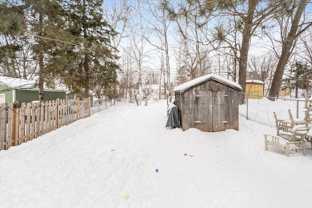 yard covered in snow with fence, an outdoor structure, and a storage unit