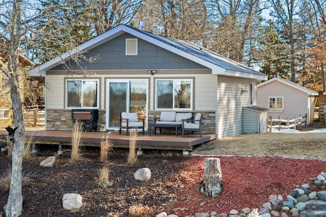 rear view of property with a wooden deck and stone siding