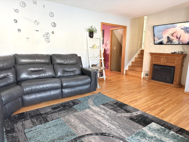 living area featuring stairway, a fireplace, and wood finished floors