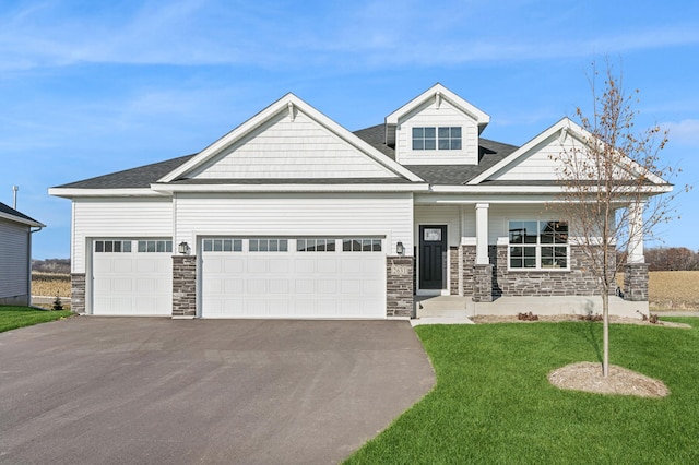 craftsman-style home featuring a garage, stone siding, aphalt driveway, and a front yard