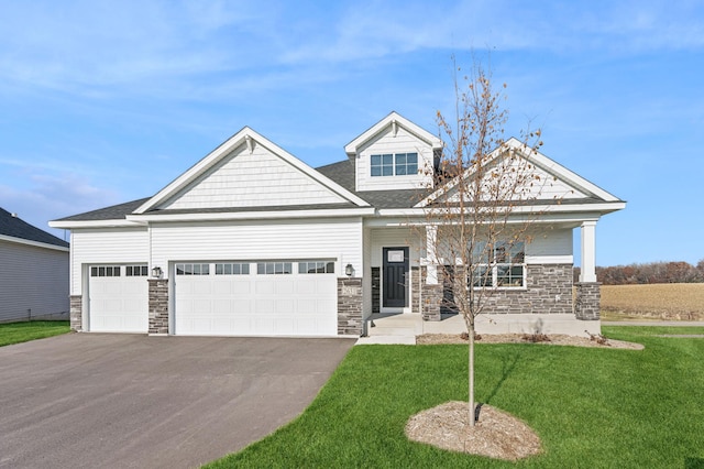 craftsman-style home featuring an attached garage, driveway, stone siding, and a front yard