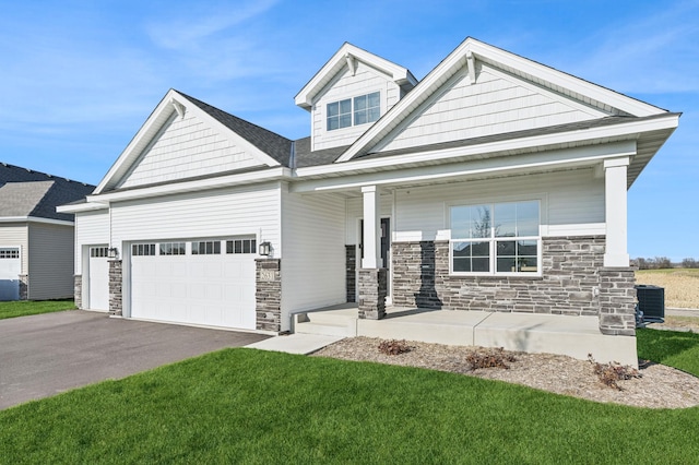 craftsman-style house with covered porch, central AC, a garage, stone siding, and driveway