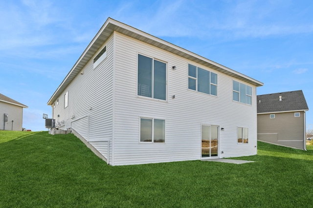 rear view of property featuring central air condition unit and a lawn