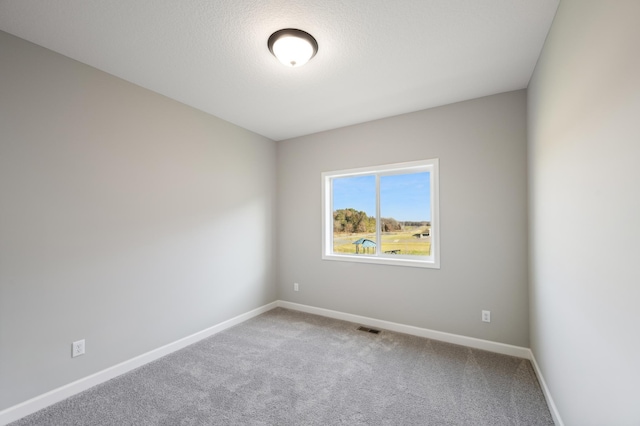 carpeted spare room with baseboards, visible vents, and a textured ceiling