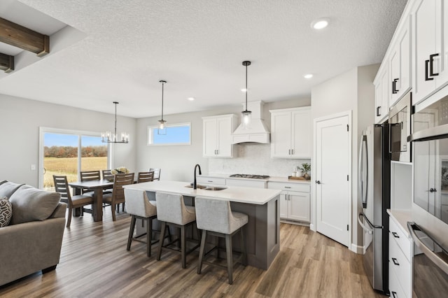 kitchen featuring light countertops, a sink, hanging light fixtures, and white cabinetry