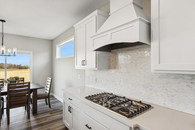 kitchen featuring premium range hood, white cabinetry, light countertops, hanging light fixtures, and stainless steel gas stovetop