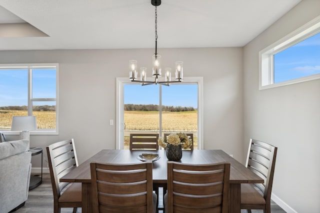 dining room featuring dark wood-type flooring, a chandelier, and baseboards