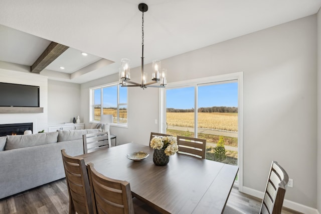 dining space featuring a notable chandelier, baseboards, dark wood-style flooring, and a glass covered fireplace