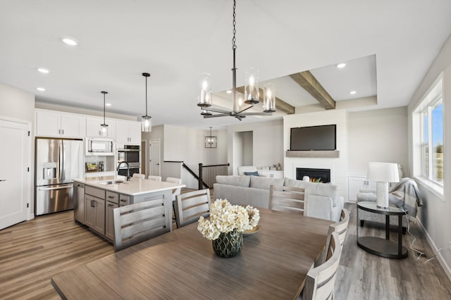 dining area featuring baseboards, beamed ceiling, wood finished floors, a fireplace, and recessed lighting