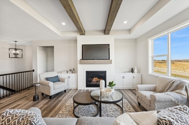 living area with a chandelier, recessed lighting, a large fireplace, wood finished floors, and beamed ceiling