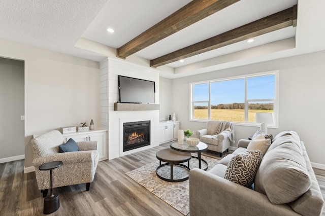 living area featuring recessed lighting, a large fireplace, wood finished floors, baseboards, and beam ceiling