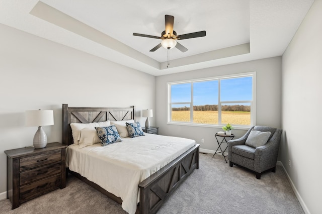 bedroom with a ceiling fan, carpet, a raised ceiling, and baseboards